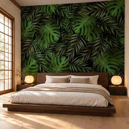 Deep green tropical leaves wall mural behind a low platform bed in a calm bedroom