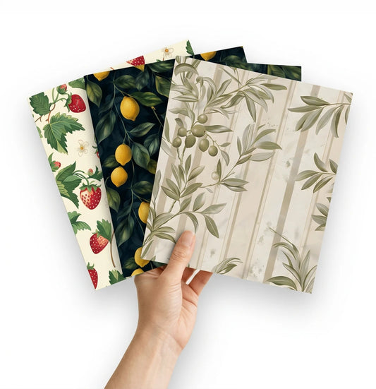 Hand holding three peel-and-stick wallpaper samples in strawberry, lemon and olive botanical patterns